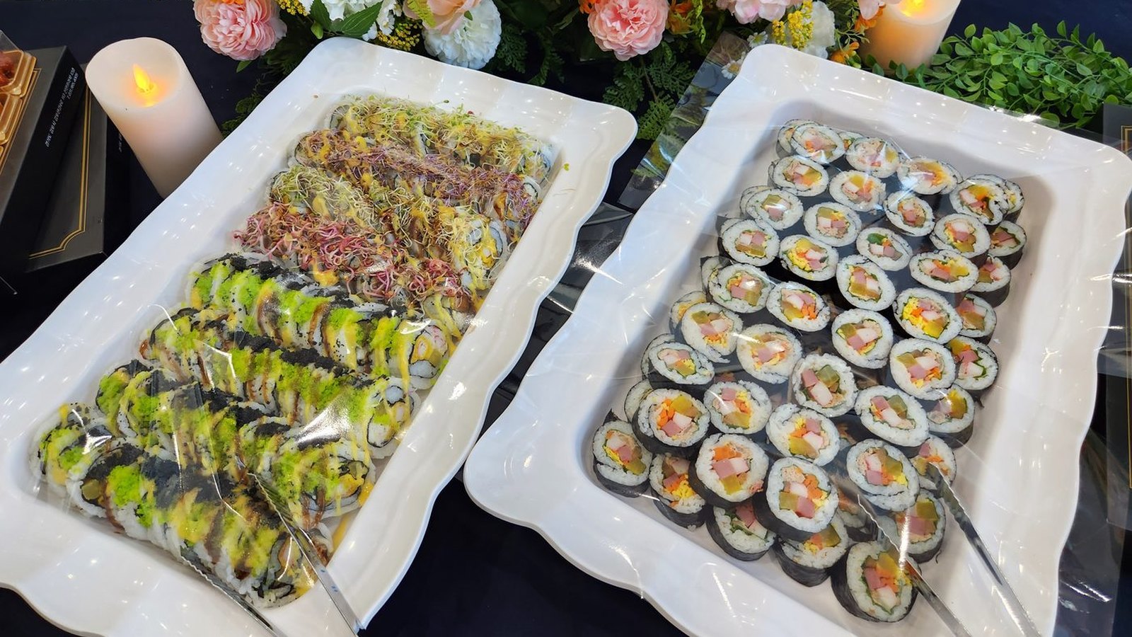 흰 물결무늬 접시 두 개에 김밥이 가득 담겨 있다. 오른쪽 접시에는 햄과 단무지, 달걀, 당근이 든 김밥이 단면을 위로 향해 촘촘히 놓였고, 왼쪽 접시에는 날치알과 새싹 채소를 올린 김밥이 줄지어 담겨 있다